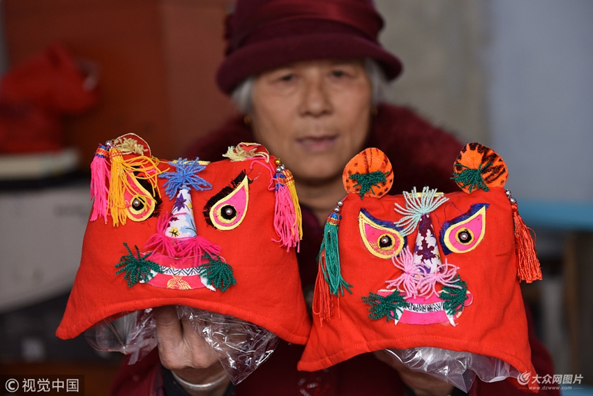 山东省日照市莒县浮来小区,今年68岁的单荣美老人展示她缝制的虎头帽