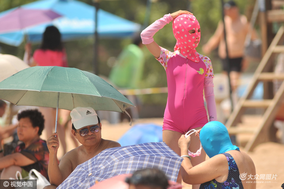 青岛海水浴场,一名头戴脸基尼面罩的学生准备与奶奶下海游泳